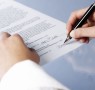 Close up of woman signing a legal document or contract, blank background.